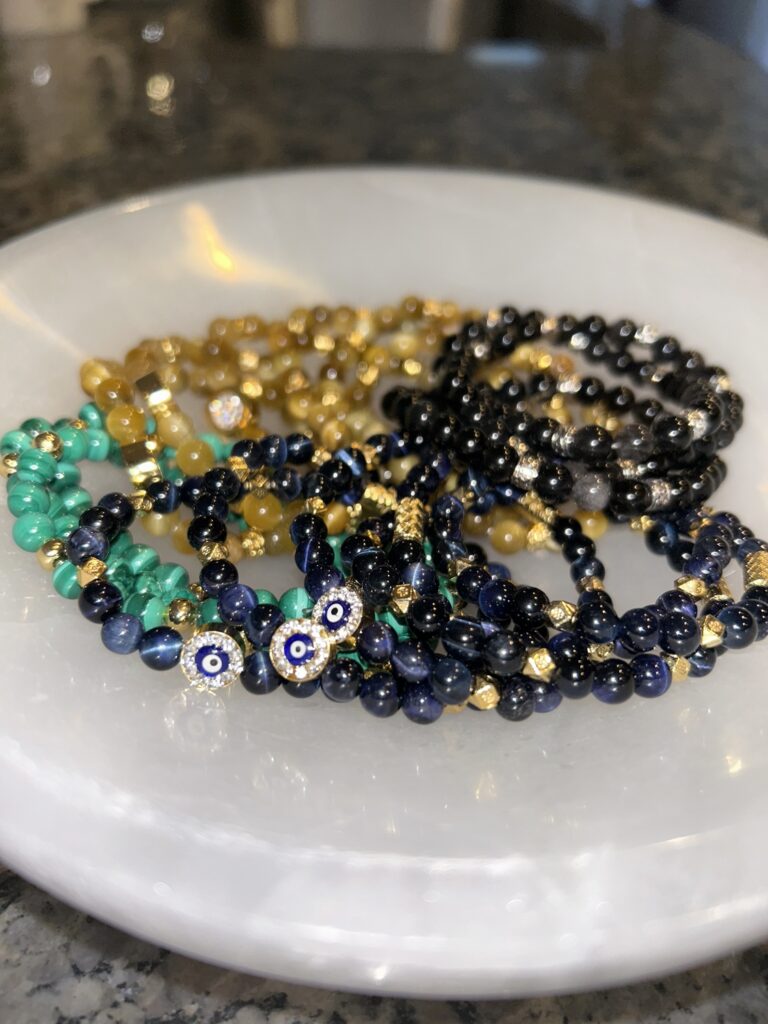 Collection of Gem Bracelets on A Plate Green Black and Yellow from the Side