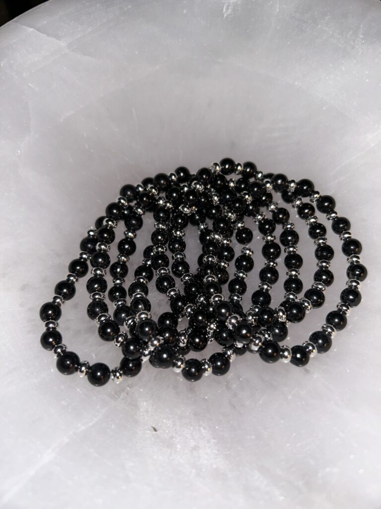 Pile of Dark Shungite Bracelets on Marble - Rotated